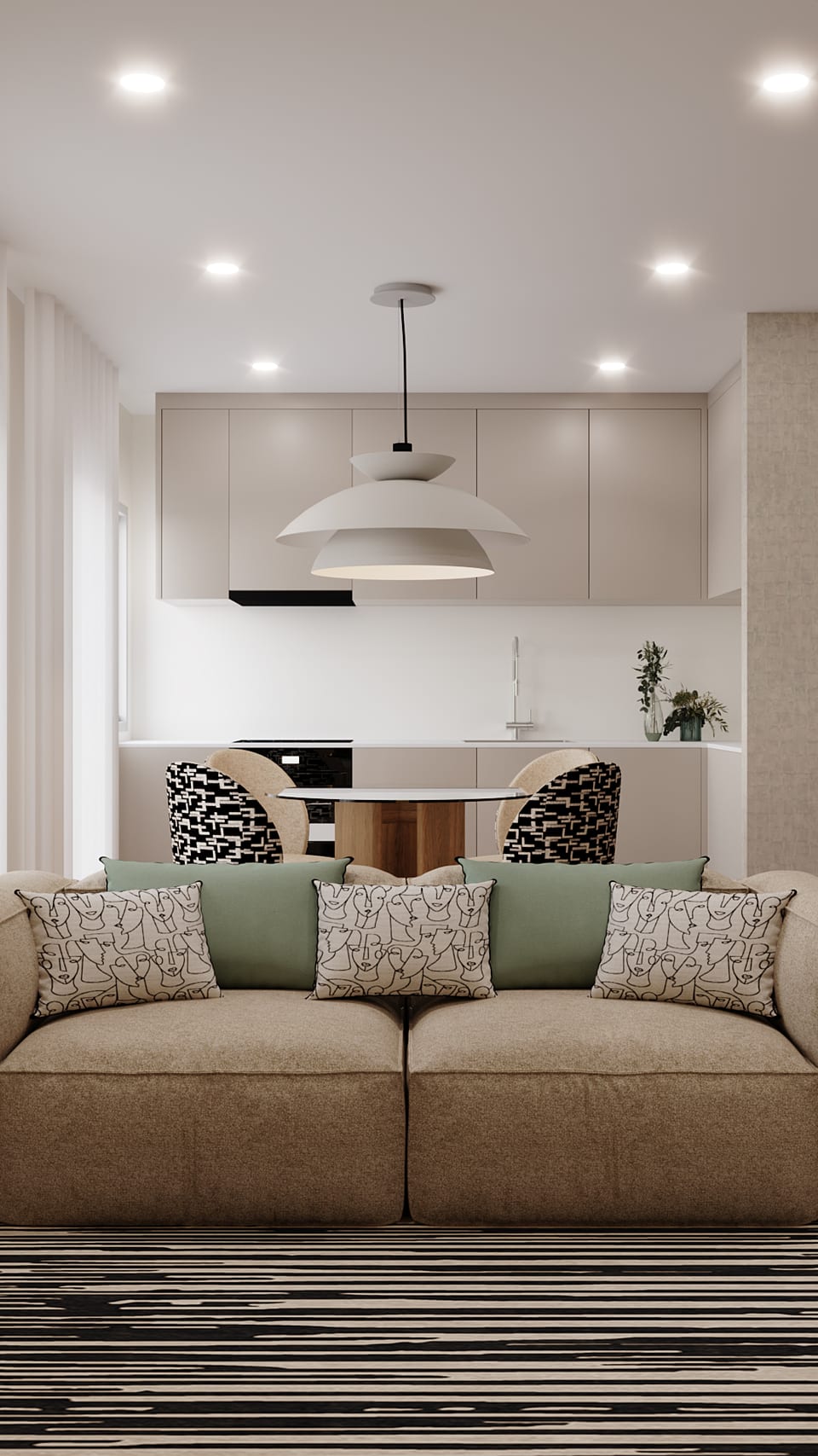 Beige open-plan kitchen, a round table in the middle and a sofa with cushions printed with faces