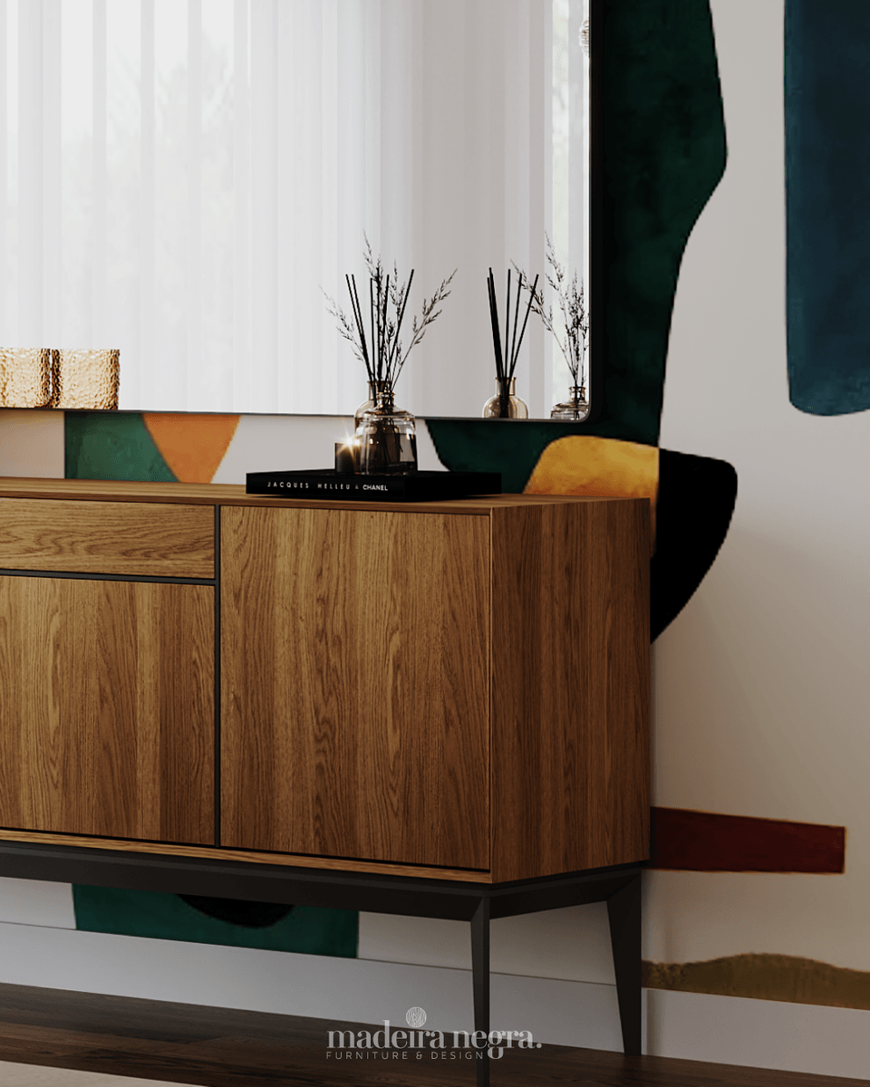 Close-up of the wooden sideboard on slim black metal legs, with a diffuser and books on top