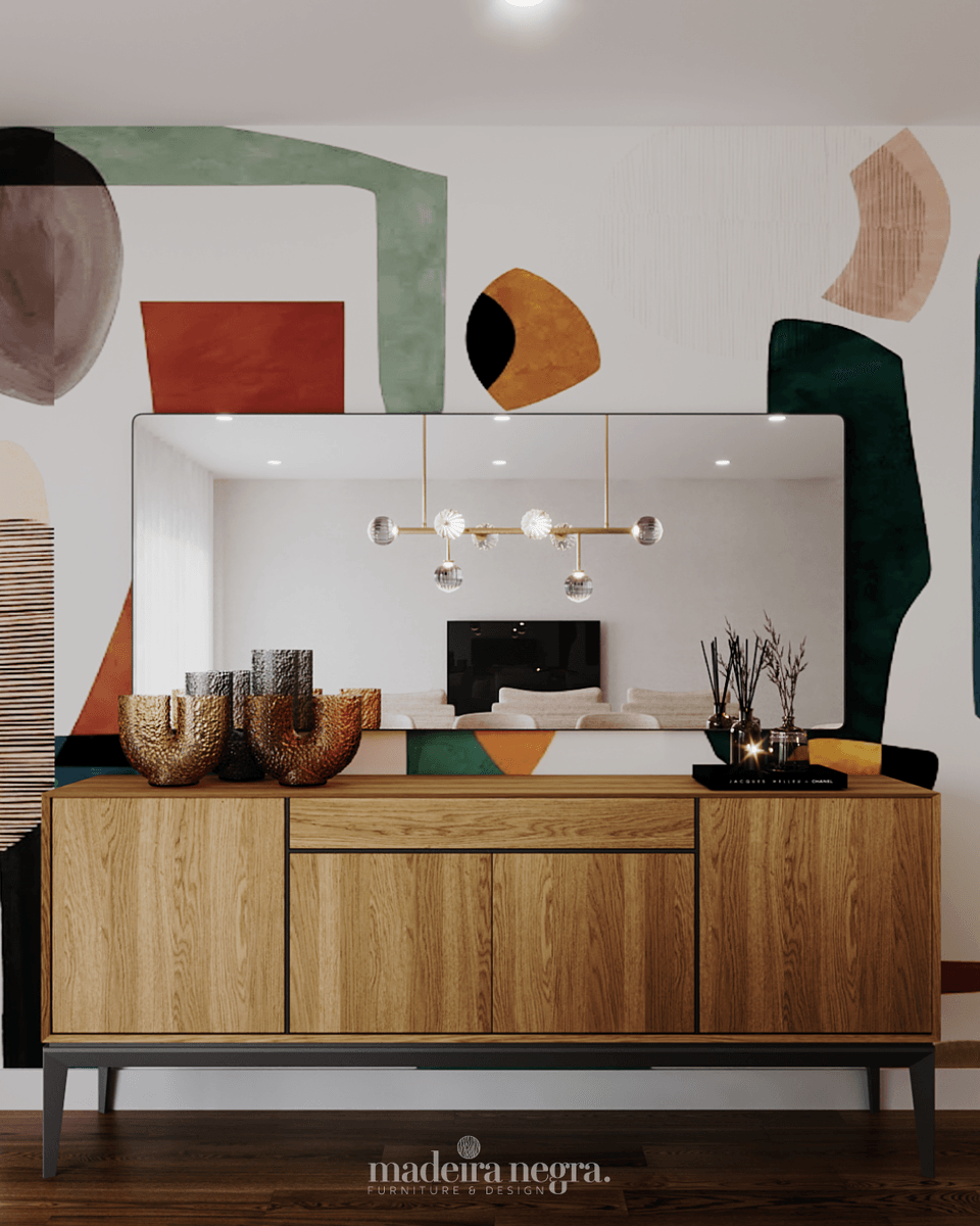 Wooden sideboard on black legs and a rectangular mirror against a wall painted with colourful shapes
